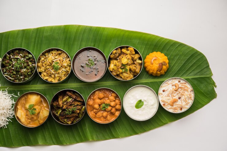 Photo 伝統的な南インド料理または大きなバナナの葉で提供される料理、フードプラッターまたは完全なターリー。セレクティブフォーカス