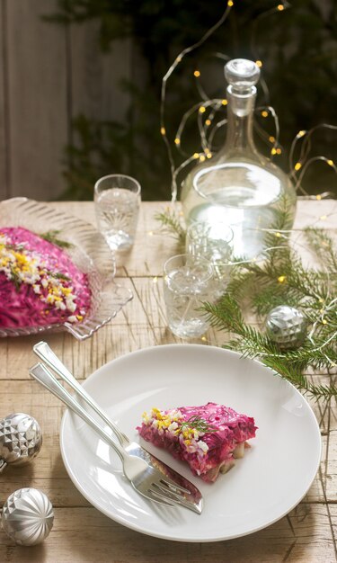 Traditional soviet festive salad of herring and vegetables, served with vodka in a new year's decoration