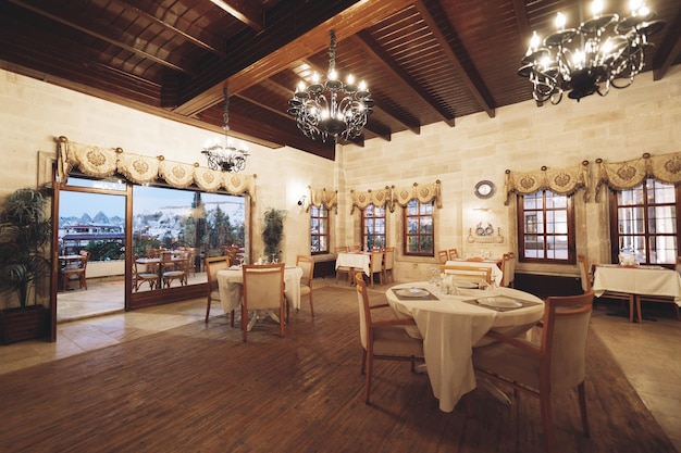 테이블과 의자가 있는 현대적인 비어 있는 대형 레스토랑의 전통적인 넓은 인테리어