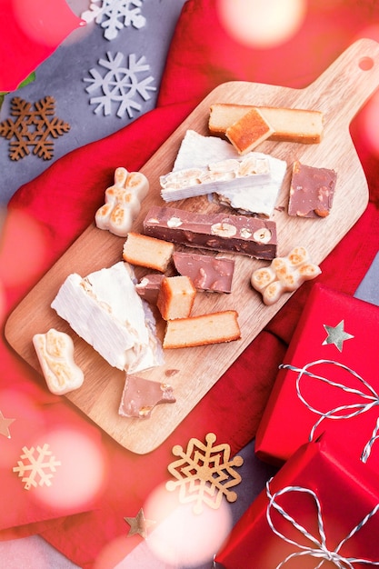 Traditional Spanish Christmas sweets turron, polvorones, mantecados with Christmas decor and red gift boxes on grey table top, copy space