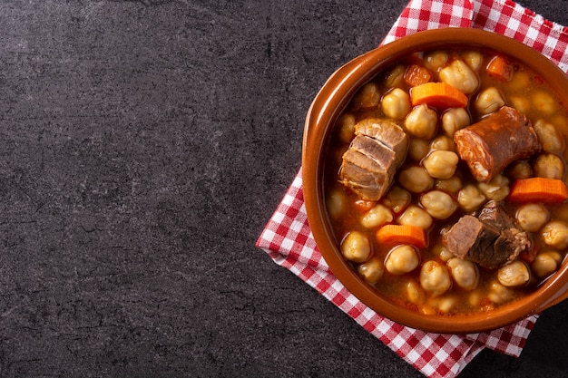 Traditional Spanish cocido madrileo in bowl on black background