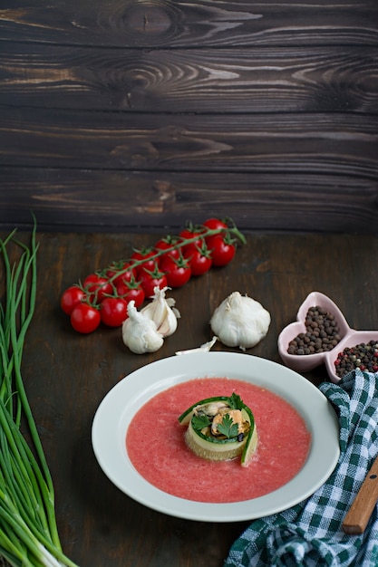 Traditional spanish cold gazpacho soup with mussels. Wooden background.