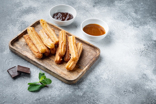 Churros tradizionali spagnoli da dessert con zucchero e cioccolato, su sfondo grigio con spazio per il testo, copyspace