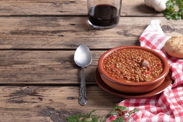 Traditional Spanish dish of lentil stew with chorizo on wooden background with copy space Healthy food concept