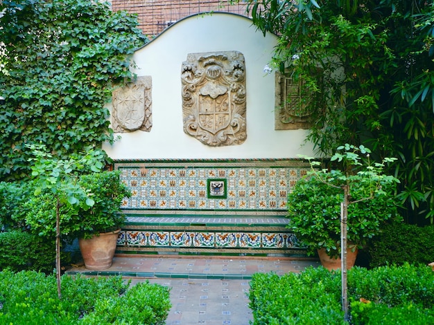 스페인 마드리드에서 자라는 타일 벤치와 선명한 녹색 식물이 있는 전통적인 스페인 정원