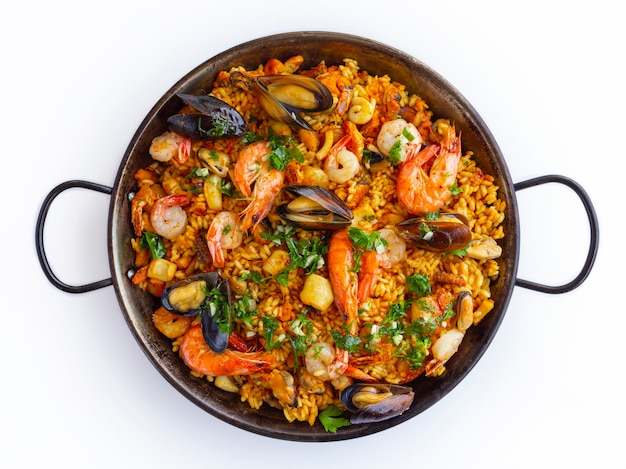 Paella spagnola tradizionale dei frutti di mare nella padella su un fondo bianco