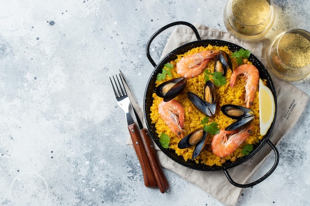 Traditional spanish seafood paella in pan with chickpeas shrimps mussels squid on light grey concret...