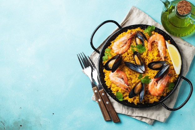 Traditional spanish seafood paella in pan with chickpeas, shrimps, mussels, squid. Top view.