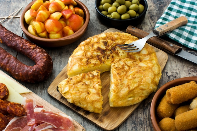 Traditional spanish tapas. Croquettes, olives, omelette, ham and patatas bravas on wooden table