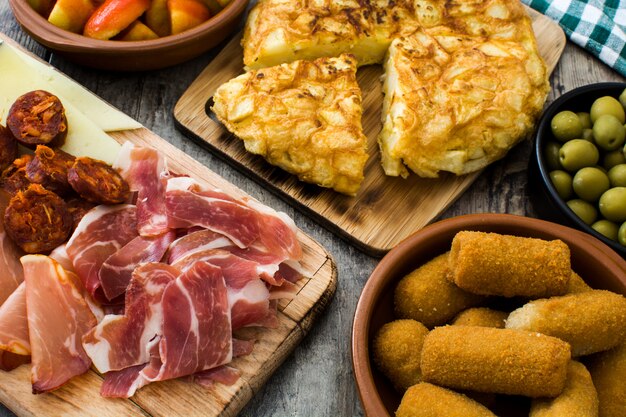 Foto tapas spagnole tradizionali. crocchette, olive, frittata, prosciutto e patatas bravas sul tavolo di legno