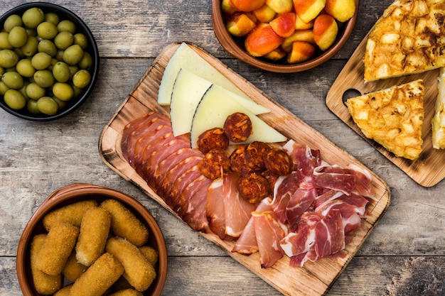 Traditional spanish tapas. Croquettes, olives, omelette, ham and patatas bravas on wooden table