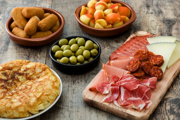 Traditional spanish tapas Croquettes, olives, omelette, ham and patatas bravas on wooden table