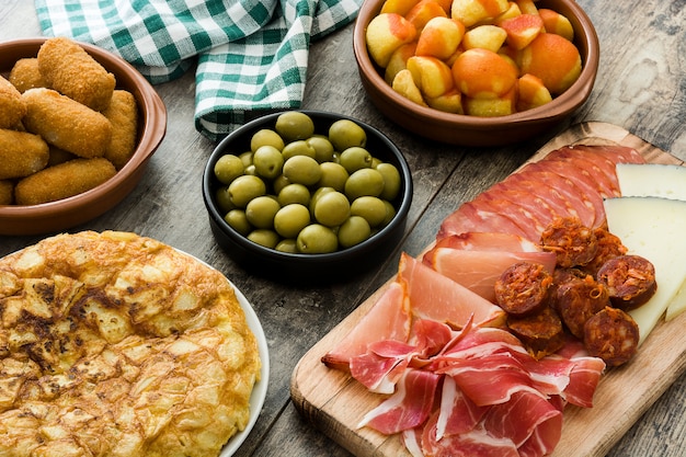 Traditional spanish tapas Croquettes, olives, omelette, ham and patatas bravas on wooden table