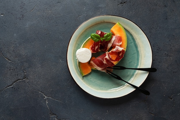 Tapas tradizionali spagnole jamon iberico con formaggio di capra, melone e miele su sfondo rustico. vista dall'alto. lay piatto