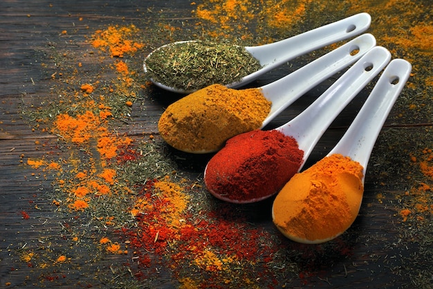 Photo traditional spices. chili pepper, turmeric, curry and dry dill in spoons on the table.