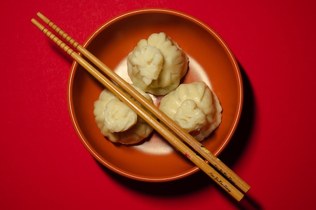 Traditional steamed dumplings khinkali and chopsticks on the red background