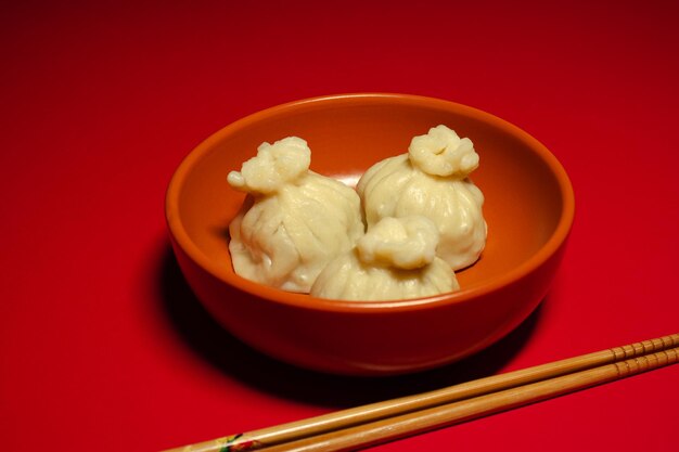 Traditional steamed dumplings khinkali and chopsticks on the red background