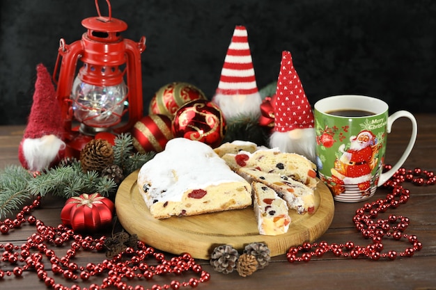 traditional stollen with decoration and cup of coffee on wooden background