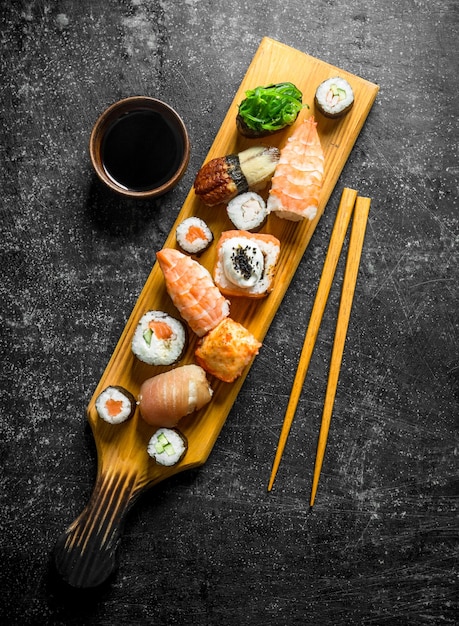 Traditional sushi rolls on a cutting board with soy sauce and chopsticks