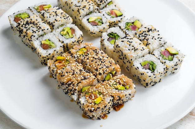 Traditional sushi rolls and maki with sesame avocado and fish Japanese food Top view On a white background