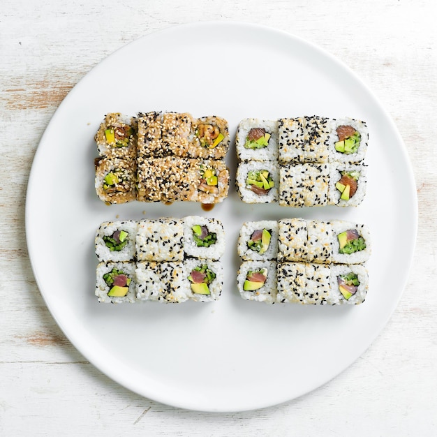 Traditional sushi rolls and maki with sesame avocado and fish Japanese food Top view On a white background