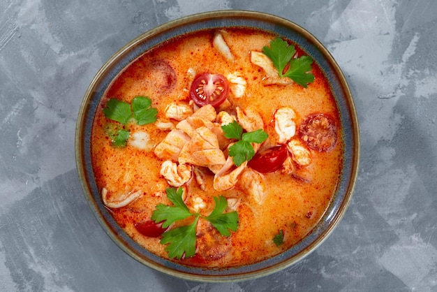 Foto cucina tradizionale thailandese tom yum zuppa piccante in ciotola nera su sfondo grigio concetto di cibo thailandese