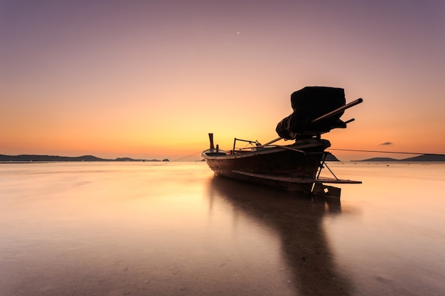 Photo traditional thai longtail boat at sunrise beach in phuket, thailand