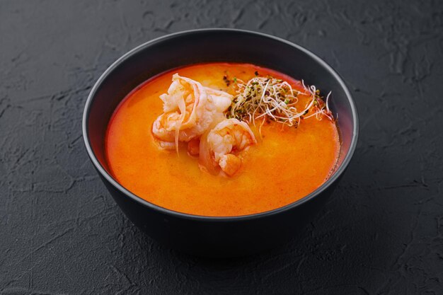 Traditional Thai soup Tom Yam in black bowl