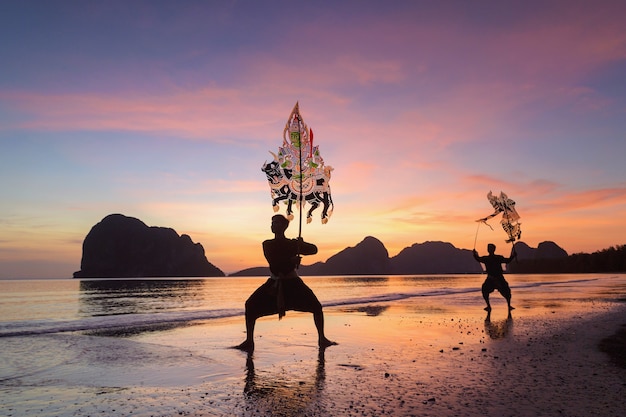 Traditional thailand shadow puppet show at beach on during\
sunset,shadow puppets