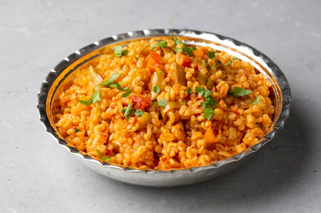 Traditional turkish bulgur pilaf with tomato sause in plate Turkish name meyhane pilavi