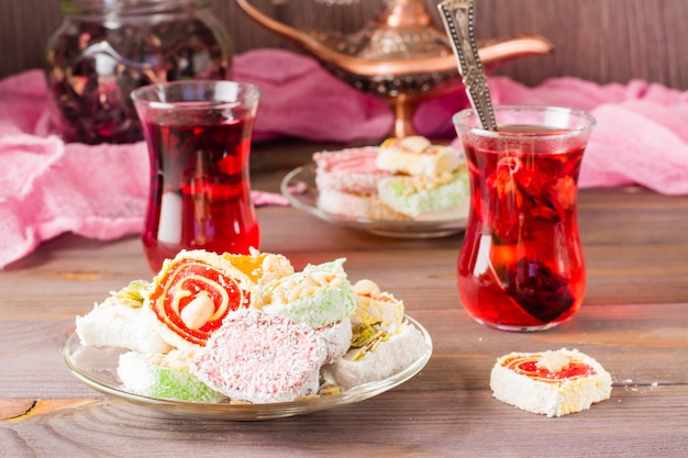 Traditional Turkish Delight on a plate and hot karkade in cups on a wooden table