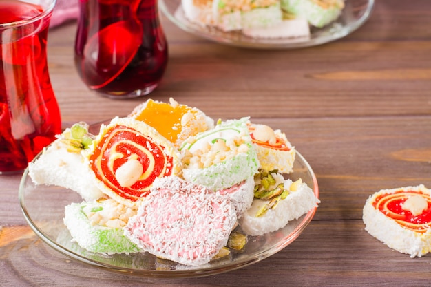 Traditional Turkish Delight on a saucer and karkade in cups on a wooden table