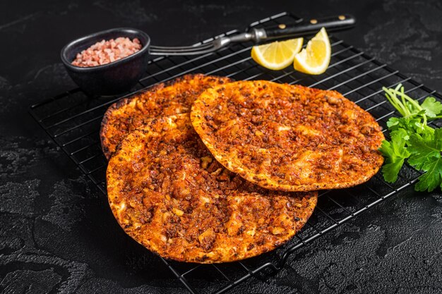 Traditional Turkish lahmacun with mince meat Black background Top view