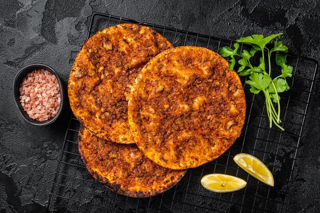 Traditional Turkish lahmacun with mince meat Black background Top view