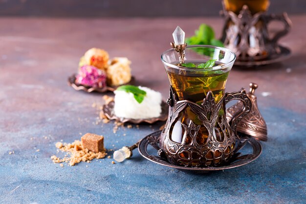 traditional turkish tea with mint leaves and sweets in a traditional glass on concrete