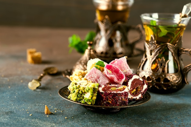 Traditional turkish tea with mint leaves and sweets in a traditional glass on concrete