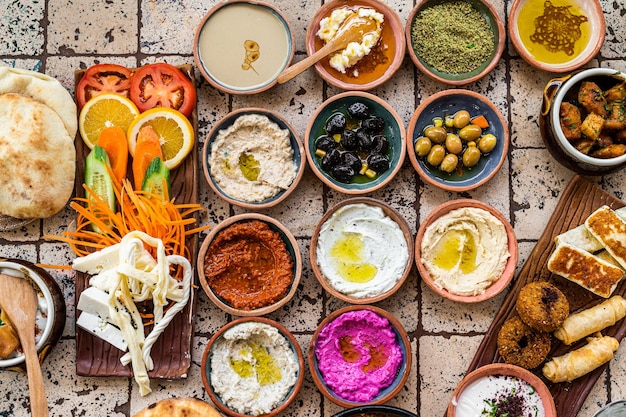 Traditional Turkish Village Breakfast on the ceramic table with pastries, vegetables, greens, spreads, cheeses, fried eggs, jams. Top view.