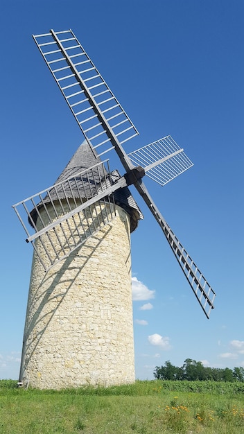 Traditional typical french windmill and green grass field in countryside