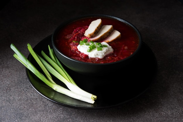 Traditional Ukrainian cuisine - borscht with sour cream and green onions, close up