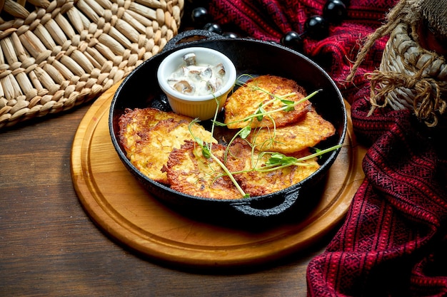 Traditional Ukrainian deruny with meat in a black pan Ukrainian cuisine Potato pancake Close up