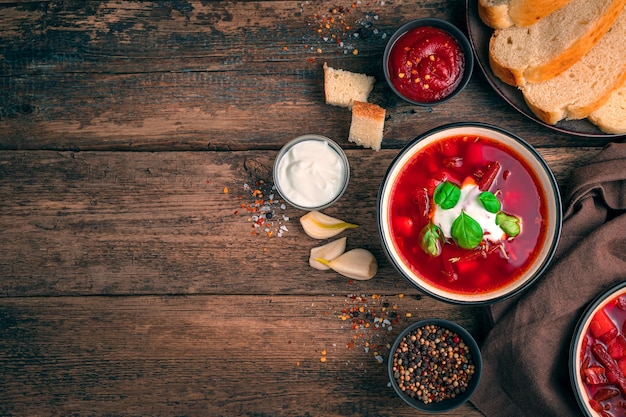 Traditional Ukrainian dish. Borscht with beetroot, sour cream and garlic on a wooden background with space for copying.
