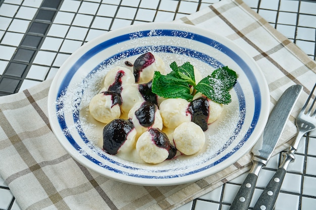 Traditional Ukrainian lazy dumplings. Dumplings with cottage cheese in a white plate on a white wooden table with berry jam. Tasty and sweet breakfast. Vareniki