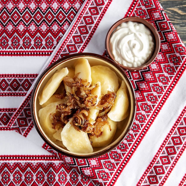 Foto gnocchi varenyki tradizionali ucraini con panna acida e latte e miele e ricotta. cucina ucraina. ravioli