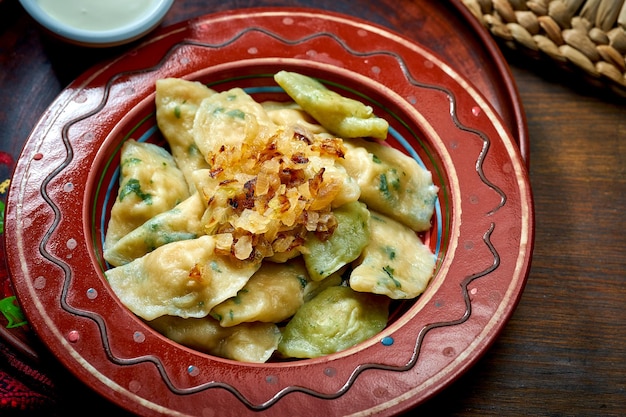 Traditional Ukrainian varenyky with meat and fried onions in clay dishes Ukrainian cuisine Close up