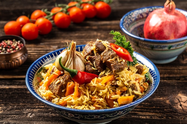 Traditional uzbek meal called pilaf. Rice with meat, carrot and onion in plate with oriental ornament, Uzbek oriental cuisine. Long banner format. space for text.