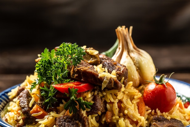 Traditional uzbek meal called pilaf. Rice with meat, carrot and onion in plate with oriental ornament, Uzbek oriental cuisine.