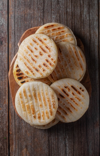 Traditional Venezuelan food arepa made from cornmeal, wooden background