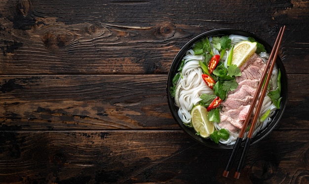 Traditional vietnamese soup pho bo with beef and noodles on wooden background top view copy space