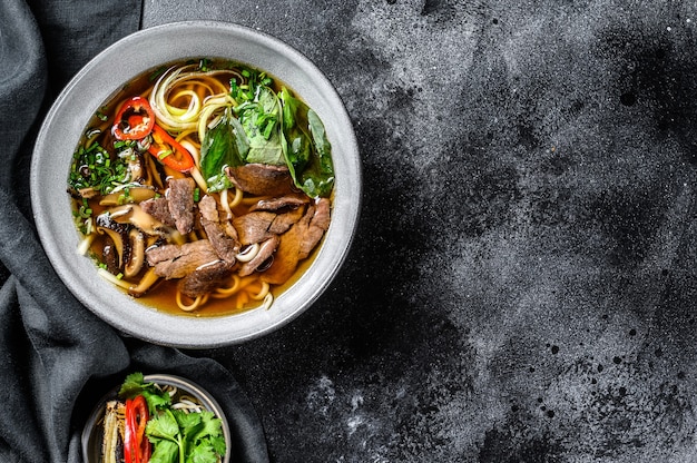 Traditional Vietnamese soup Pho bo with herbs, meat, rice noodles, broth. Black background