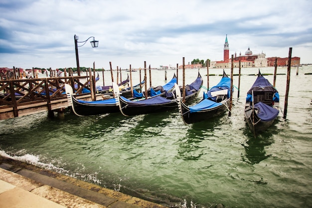 Traditional view from San Marco, Venice, Italy. Blue gondolas parked on Canal Grande, San Giorgio Maggiore church at the background